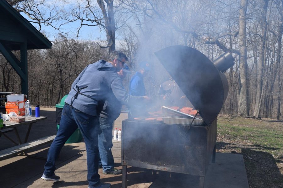 Science teacher Will Young, athletic director  Mark Proccer, physical education teacher Chris Frankenfield, and business teacher Jim Parks grill food at the senior picnic on April 2. Young said, “When the wind isn’t blowing in my face… this is way better than proctoring the ACT.” 