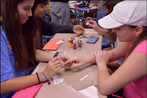 Junior Eva Jansen gives junior Anna Zwibelman a manicure, as they practice for the event on Oct. 10. GlamourGals will be going to Friendship Village in Sunset Hills on Olive Boulevard for their first outing.
