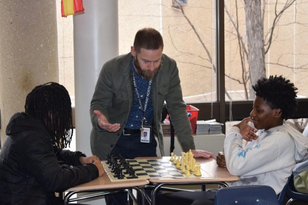 Spanish teacher Adam Stiller teaches chess strategies to sophomores Ja’khi Bunch and Brice Tyler . 