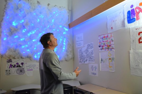 English teacher Kevin Morton shows off the creative decorations in his classroom. Some of these decorations include a light up cloud, a projector that displays planets, fall leaves, and many different types of lights. 